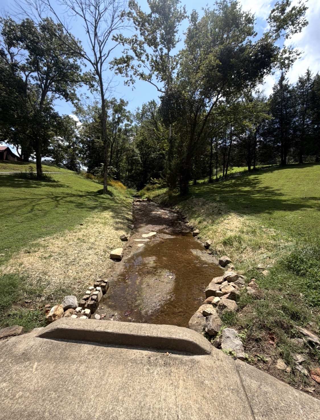 Creek bed and banks cleared of overgrowth with rock along the edges