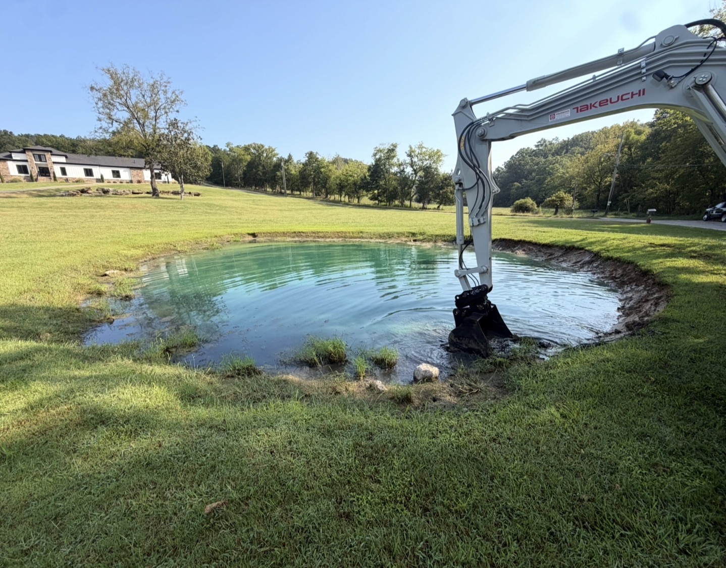 Excavator reshaping the bank of a pond on a manicured property