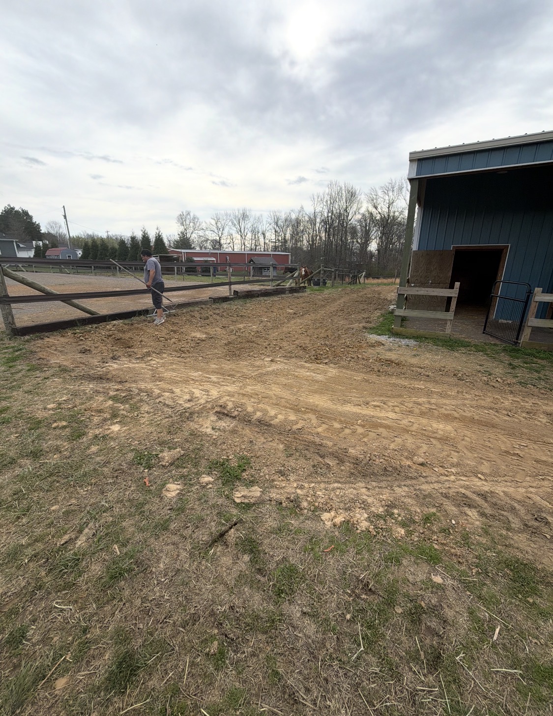 Graded ground beside a barn and fenced paddock